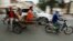 A Cambodian worker, third from left, views his mobile phone on a motor cart forwarding to work, in Phnom Penh, Cambodia, Tuesday, Aug. 11, 2015. Mobile phones are more popular than desktop computers in Cambodia. (AP Photo/Heng Sinith)