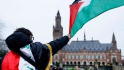 Seorang pria mengibarkan bendera Palestina ketika massa melakukan demonstrasi pada hari sidang publik yang diadakan oleh Mahkamah Internasional (ICJ) di Den Haag, Belanda, 21 Februari 2024. (Foto: Reuters)
