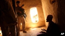 FILE - U.S. Army soldier and an Afghan translator interrogate a person in the Bagh village of Khakeran Valley, Zabul province, Afghanistan.