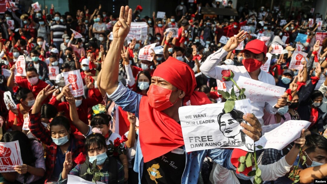 People show the three-finger salute and hold signs demanding the release of elected leader Aung San Suu Kyi as they take part in a protest against the military coup, in Yangon, Myanmar, Feb. 7, 2021