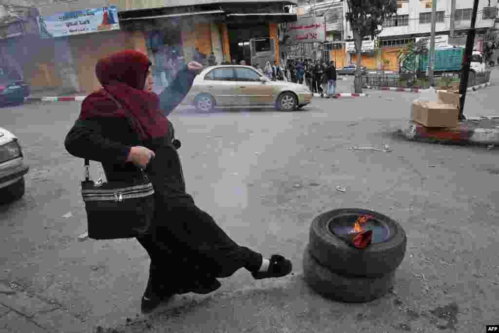 A Palestinian demonstrator kicks tires during clashes with Israeli security forces near a checkpoint in the city center of the West Bank town of Hebron.