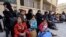 A picture taken on March 13, 2018 shows evacuated civilians and children sitting in the yard of a school lying on the government side of the Wafideen checkpoint on the outskirts of the Syrian capital Damascus neighboring the Eastern Ghouta enclave.