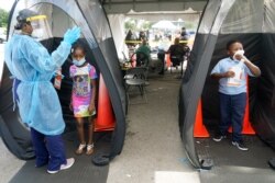 Wenderson Cerisene, 7, right, and his sister Dorah, 9, wait to get tested for COVID-19, Aug. 31, 2021, in North Miami, Florida. Florida schools are seeing a rise in COVID-19 cases forcing of students and teachers to quarantine.