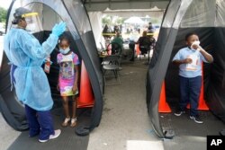 Wenderson Cerisene, 7, right, and his sister Dorah, 9, wait to get tested for COVID-19, Aug. 31, 2021, in North Miami, Florida. Florida schools are seeing a rise in COVID-19 cases forcing of students and teachers to quarantine.