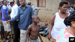 A young boy joins other onlookers at the scene where five dead bodies were found in a street in the Cibitoke neighborhood of the capital Bujumbura, Burundi, Dec. 9, 2015. 