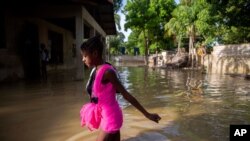 A girl wades towards her flooded home the day after the passing of Tropical Storm Laura in Port-au-Prince, Haiti, Aug. 24, 2020.