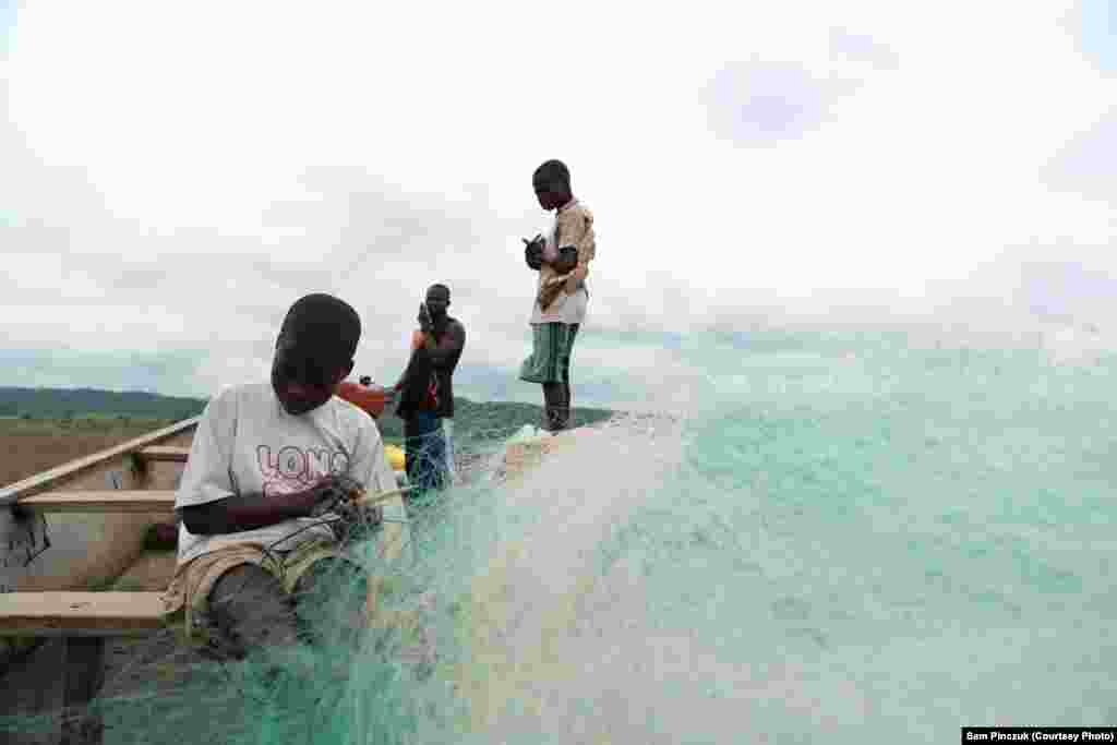 Here child slaves nervously prepare a fishing net under the watchful eye of a fisherman.