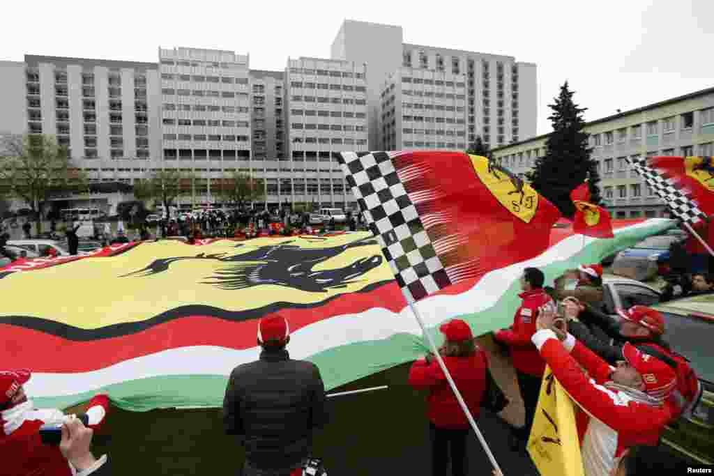 Fans from France, Italy and Germany display a giant Ferrari flag as they attend a silent 45th birthday tribute to seven-times former Formula One world champion Michael Schumacher in front of the CHU hospital emergency unit in Grenoble, French Alps where Schumacher is hospitalized.