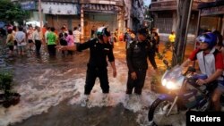 FILE - A policeman directs traffic as residents move through the floods as it advances into central Bangkok.