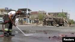 A fireman clears blood and debris as NATO soldiers stand at the site of an attack in Helmand province, Afghanistan, August 28, 2013.