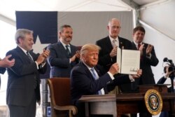 President Donald Trump holds up a permit for energy development after signing it during a visit to the Double Eagle Energy oil rig, July 29, 2020, in Midland, Texas. Sen. Ted Cruz, R-Texas, stands second from left.