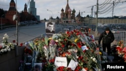 Seorang pria berjalan melewati karangan bunga di lokasi pembunuhan pengkritik Kremlin, Boris Nemtsov. Dia dibunuh pada 27 Februari 2015.