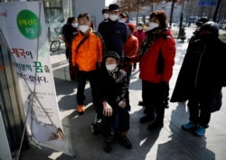 People wearing protective masks read a notice about the sale of masks at a post office amid the rise in confirmed cases of coronavirus, in Daegu, South Korea, March 5, 2020.