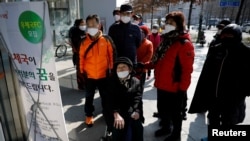 People wearing protective masks read a notice about the sale of masks at a post office amid the rise in confirmed cases of coronavirus, in Daegu, South Korea, March 5, 2020.