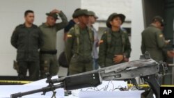 FILE - Police officers stand behind a seized weapon at the police station in Necocli, Colombia, March 11, 2015. Gen. Ricardo Restrepo the commander of counter-narcotics police said that ammunition, weapons and about 170 kilograms of cocaine belonging to the "Los Usuga" criminal gang were seized in the rural town of Necocli, in Antioquia state.