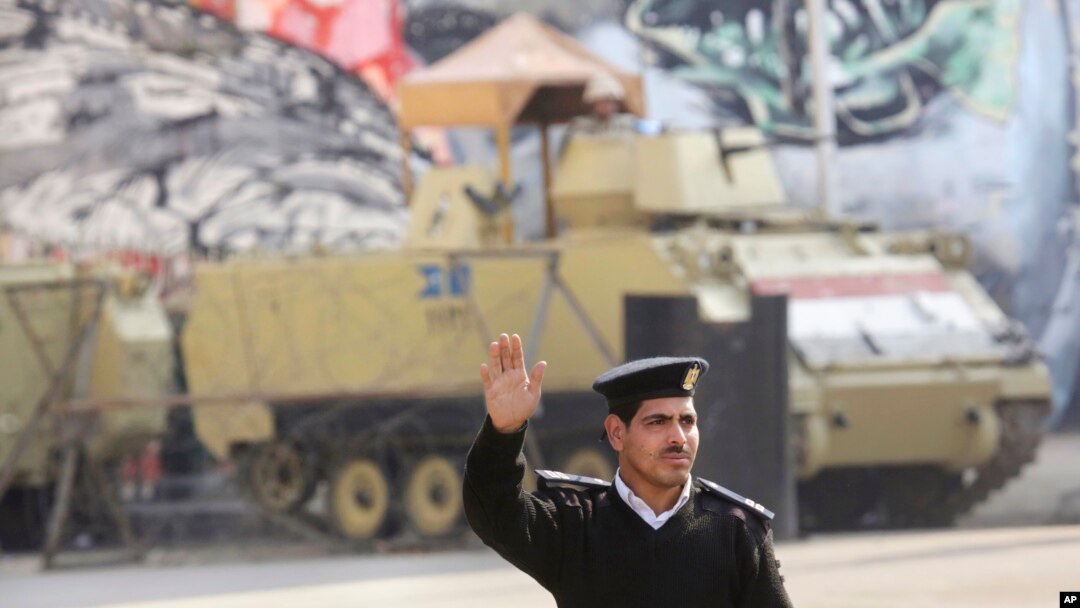 Seorang polisi di depan kendaraan lapis baja di dekat Lapangan Tahrir di Cairo, Mesir, 28/11/2014. Bentrokan di Kairo pada hari Jumat menewaskan setidaknya 3 orang. 