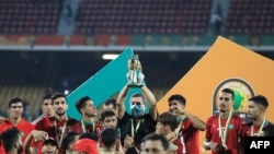 FILE - Morocco's coach Houcine Ammouta (C) holds up the trophy after his team's win during the African Nations Championship (CHAN) final football match between Morocco and Mali at Stade Ahmadou Ahidjo in Yaounde, Cameroon, Feb. 7, 2021.