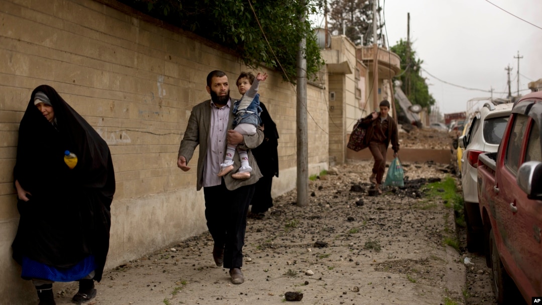 Seorang anak dan keluarganya berupaya menyelamatkan diri saat berlangsungnya pertempuran di distrik Yarmouk, wilayah barat Mosul, 11 April 2017. 