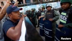 Police officers block a street as protesters demand the release of five opposition members of parliament, near the Phnom Penh Municipal Court in central Phnom Penh, July 16, 2014. 