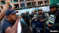 Police officers block a street as protesters demand the release of five opposition members of parliament, near the Phnom Penh Municipal Court in central Phnom Penh, July 16, 2014. 