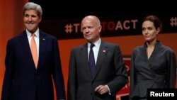 From left, U.S. Secretary of State John Kerry, Britain's Foreign Secretary William Hague and actress and campaigner Angelina Jolie gather at a summit to end sexual violence in conflict in London, June 13, 2014.