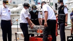 Members of National Transportation Safety Committee carry a box containing the cockpit voice recorder of Sriwijaya Air flight SJ-182 that crashed in January, after a press conference at Tanjung Priok Port in Jakarta, Indonesia, March 31, 2021.