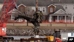 Para petugas mengangkat bagian badan helikopter Black Hawk di dekat lokasi tabrakan di udara antara helikopter nahas itu dan pesawat jet American Airlines di Bandara Nasional Ronald Reagan Washington, di Arlington, 6 Februari 2025. (Foto: Jose Luis Magana/AP Photo)