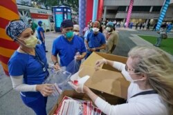 FILE - The founder of the New York nonprofit Cut Red Tape 4 Heroes, Rhonda Roland Shearer, right, helps hand out free personal protective equipment to health care workers outside Jackson Memorial Hospital, Sept. 22, 2020, in Miami.