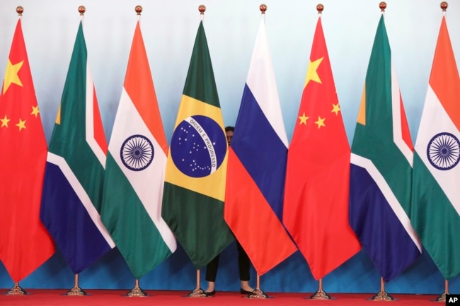 Staf merapikan bendera negara-negara BRICS sebelum foto bersama pada KTT BRICS di Xiamen, China, 4 September 2017. (Wu Hong/Pool Photo via AP)