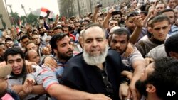 FILE - Egyptian lawyer and candidate for the Egyptian presidency Hazem Salah Abu Ismail, center, is guarded by his supporters at Tahrir Square during a protest against the ruling military council, in Cairo, Egypt, Oct. 28, 2011.