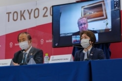 اولمپک کمیٹی کے نائب صدر جان کوٹس ورچوئل میٹنگ میں ٹی وی سکرین پر دکھائی دے رہیں جب کہ بائیں جانب ٹوکیو اولمپکس سی ای او توشیرو موٹو ہیں اور دائیں طرف ٹوکیو گیمز 2020 کے صدر سیکو ہاشی موتو ہیں۔ 21 مئی 2021