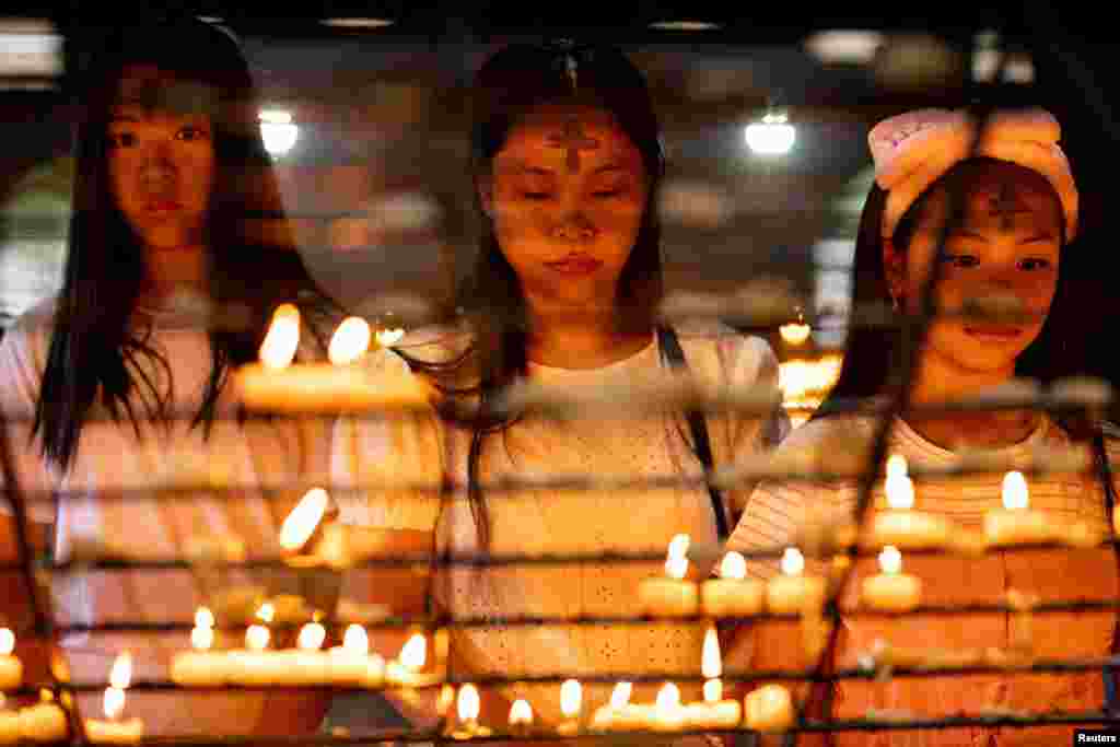 Filipino Catholics marked with ash crosses on their foreheads pray after offering candles on Ash Wednesday, at Baclaran Church, in Paranaque City, Metro Manila, Philippines.