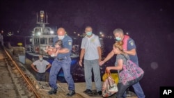FILE - Migrants are assisted by Romanian border policemen in the Black Sea port of Constanta, Romania, early Wednesday, Sept. 13, 2017. 