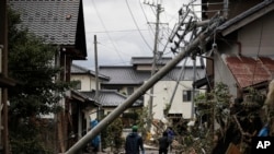 Residents walk along the mud-covered road in a neighborhood devastated by Typhoon Hagibis , Oct. 15, 2019, in Nagano, Japan.