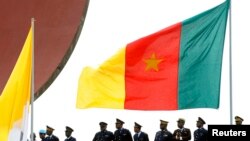 FILE - Cameroonian police stand near a national flag.