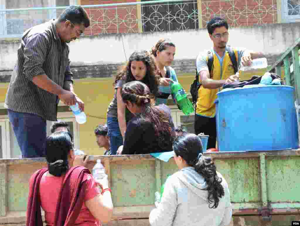 Volunteers of the humanitarian community service group, the Eureka Leo Club, distribute drinking water at Kalimati, Kathmandu, April 27, 2015. (Bikas Rauniar/VOA)