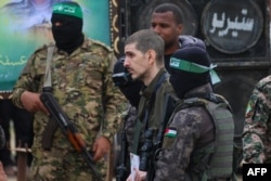 Palestinian Hamas fighters escort Israeli hostage Or Levy on a stage before handing him over to a Red Cross team in Deir el-Balah, central Gaza, on Feb. 8, 2025, as part of the fifth hostage-prisoner exchange of a fragile ceasefire.