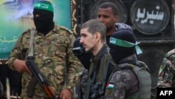 Beberapa militan Hamas Palestina mengawal sandera Israel Or Levy di atas panggung sebelum menyerahkannya kepada tim Palang Merah di Deir el-Balah, Gaza tengah, pada 8 Februari 2025 (foto: dok). 