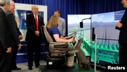 
Presiden AS Donald Trump memperhatikan Rita Urmie (duduk), seorang siswa, mengoperasikan simulator di Kirkwood Community College di Cedar Rapids, Iowa, 21 Juni 2017. (Foto: Reuters)
