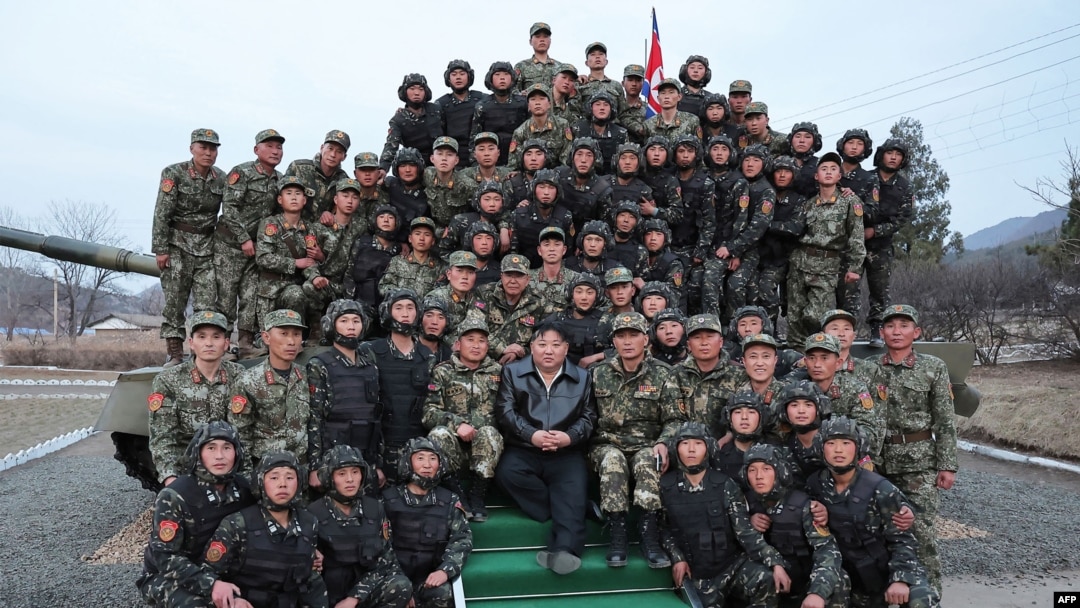 Pemimpin Korea Utara Kim Jong Un (tengah) berfoto bersama para tentara dari unit Seoul Ryu Kyong Su ke-105 di sebuah lokasi di Korea Utara, pada 24 Maret 2024. (Foto: KCNA via KNS/AFP)