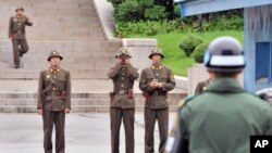 North Korean soldiers look towards the south as a South Korean soldier (R) stands guard in the demilitarized zone separating the two Koreas, July 15, 2011.