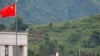 FILE - Pasukan pemerintah Myanmar berdiri di atas atap di sisi Myanmar, dekat bendera China dari kota perbatasan China Nansan di provinsi Yunnan, China barat daya, Minggu, 30 Agustus 2009. (Ng Han Guan/AP)