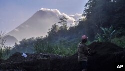 Seorang pria bekerja di tambang galian pasir dengan latar Gunung Merapi, Selasa, 22 Mei 2018. Status Gunung Merapi telah dinaikan menjadi Waspada (level 2), dari Normal (level 1).