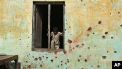 An Indian boy prepares to climb out the window of a house, the walls of which were damaged in mortar shell attack at Jora Farm village, in Ranbir Singh Pura, south of Jammu, India, Feb. 9, 2015. 