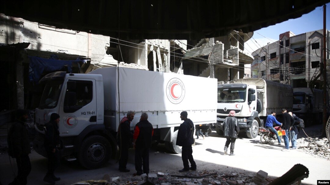 Beberapa orang terlihat di sekitar truk bantuan Bulan Sabit Merah di kota terpencil Douma, Ghouta Timur, Damaskus, Suriah, 9 Maret 2018.