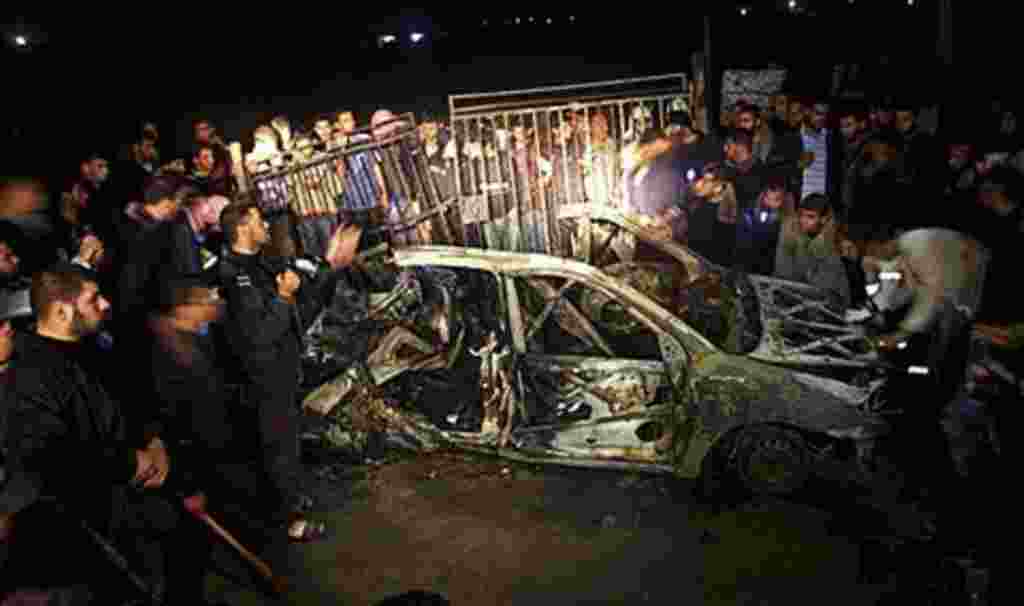 Palestinians surround the wreckage of a vehicle following an Israeli airstrike that killed three of Hamas militants near Deir Al Balah, central Gaza Strip, April 2, 2011