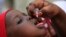 FILE - An unidentified health official administers a polio vaccine to a child in Kawo Kano, Nigeria, April 2014.