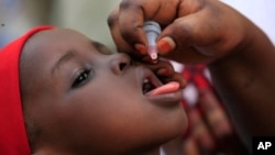 FILE - An unidentified health official administers a polio vaccine to a child in Kawo Kano, Nigeria, April. 13, 2014.