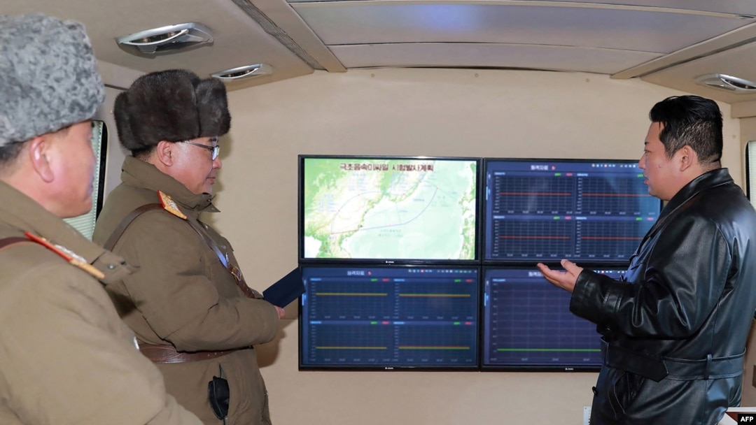 Pemimpin Korea Utara Kim Jong-un (kanan) berbicara dengan pejabat militer selama pengamatan terhadap apa yang dikatakan media pemerintah sebagai uji tembak rudal hipersonik di sebuah lokasi yang dirahasiakan di Korea Utara (12/1). (KCNA via KNS/AFP)