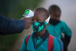 A boy's temperature is checked as he enters a school amid the coronavirus pandemic, in Johannesburg, South Africa, July 7, 2020.